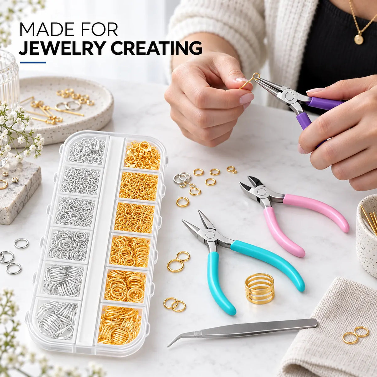 PHYHOO jewelry findings tool kit in use - jeweler using purple round-nose pliers to open a gold jump ring on a marble workbench with findings box, teal pliers, pink diagonal cutter, tweezers and ring opening tool